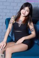 A woman sitting on a blue chair with tattoos on her arms.