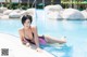 A woman in a pink bikini laying on the edge of a pool.