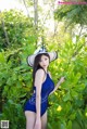 A woman in a blue swimsuit and a white hat posing for a picture.