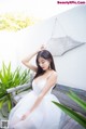 A woman in a white dress sitting on a wooden bench.