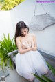 A woman in a white dress sitting on a wooden bench.