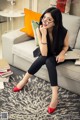 A woman sitting on a couch with a laptop and glasses.