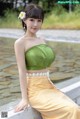 A woman in a green top and yellow skirt posing for a picture.