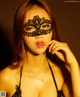 A woman wearing a black lace mask posing for a picture.