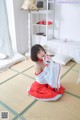 A woman in a red and white dress sitting on a tatami mat.