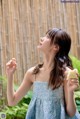 A woman in a blue dress holding a piece of cake.