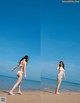 A woman in a white bikini standing on a beach.