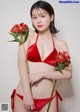 A woman in a red bikini holding a bunch of flowers.