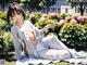 A woman in a white kimono sitting in the grass.