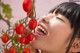 A young girl smelling a bunch of tomatoes on a plant.