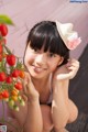 A woman sitting on the ground next to a bunch of tomatoes.