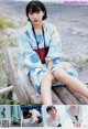 A woman in a blue kimono sitting on a wooden bench.