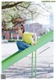 A woman sitting on a green slide in a park.