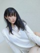 A woman with long black hair wearing a white shirt.