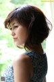 A woman in a blue dress looking out a window.