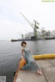 A woman in a long dress sitting on a dock by the water.