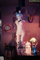 A naked woman sitting at a bar with a dart board in the background.