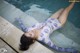 A woman laying on the edge of a swimming pool.