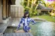 A woman in a blue and white floral swimsuit sitting on a wooden dock.