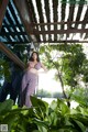 A woman standing in front of a window in a garden.