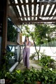 A woman standing in front of a window with plants.