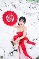 A woman in a red dress holding a red fan in the snow.