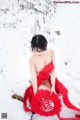 A woman in a red dress sitting in the snow.