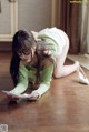 A woman laying on the floor reading a piece of paper.