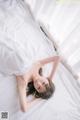 A woman laying on top of a bed covered in white sheets.