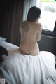 A woman sitting on a bed with a tattoo on her back.