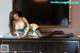 A woman in a green lingerie sitting on top of a dresser.