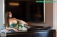 A woman in a green lingerie sitting on top of a dresser.