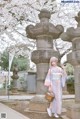 A woman in a kimono standing in front of a stone pillar.