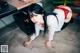 A woman in a white shirt and red lingerie crouching on the floor.