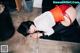 A woman in a red and white shirt and black stockings laying on the floor.