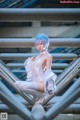 A woman with blue hair sitting on a metal structure.