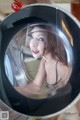 A woman is reflected in a washing machine. 