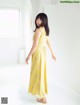 A woman in a yellow dress standing in a white room.