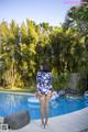 A woman in a blue and white floral swimsuit standing by a swimming pool.