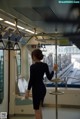 A woman in a black dress standing on a train.