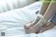 A woman with a bandage on her foot sitting on a bed.