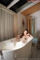 A woman sitting in a bathtub with foam in it.