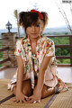 A woman in a kimono sitting on a bamboo mat.