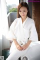 A woman in a white robe sitting on a bathtub.