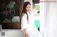 A woman in a white robe sitting on a bathtub.