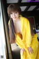 A woman in a yellow robe posing for the camera.