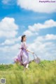 A woman in a purple dress is walking through a field.