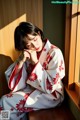 A woman in a kimono sitting on a window sill.