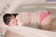 A woman in a pink bikini laying in a bathtub.