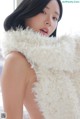 A woman in a white fur vest posing for a picture.